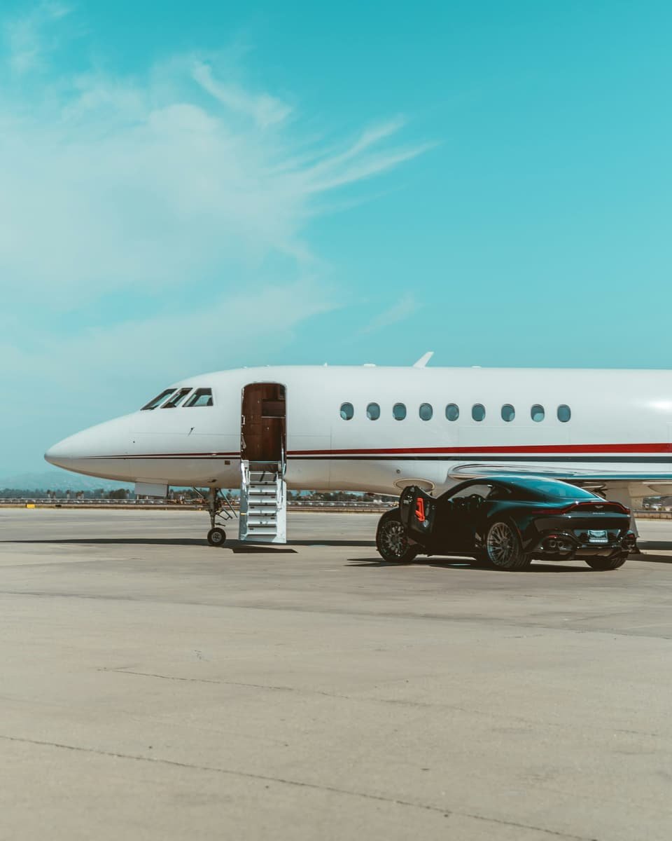 Jet privé sur le tarmac, voiture de sport garée au pied de la passerelle